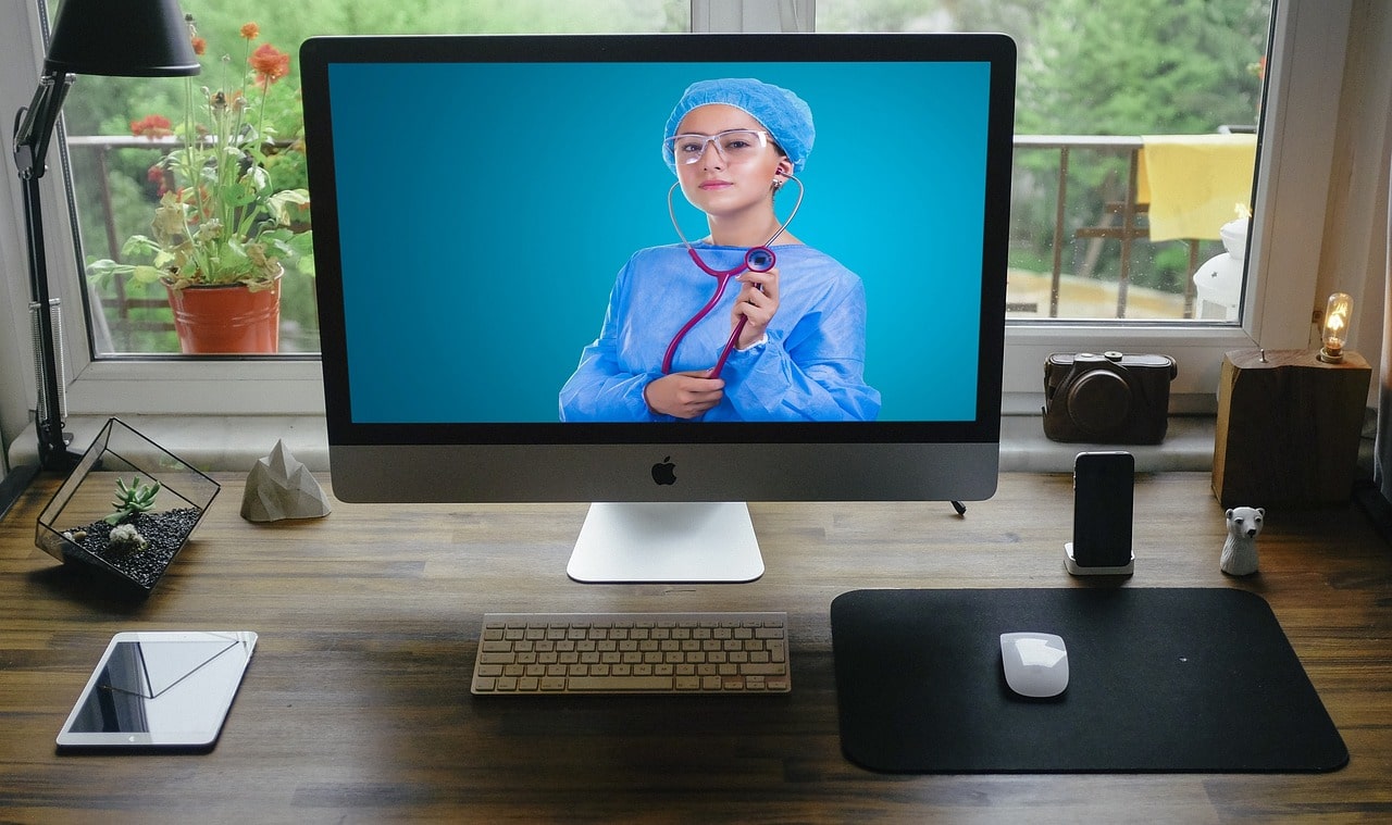 Remote-Healthcare-Blog-Header-Woman-Wearing-Scrubs-On-PC-Monitor